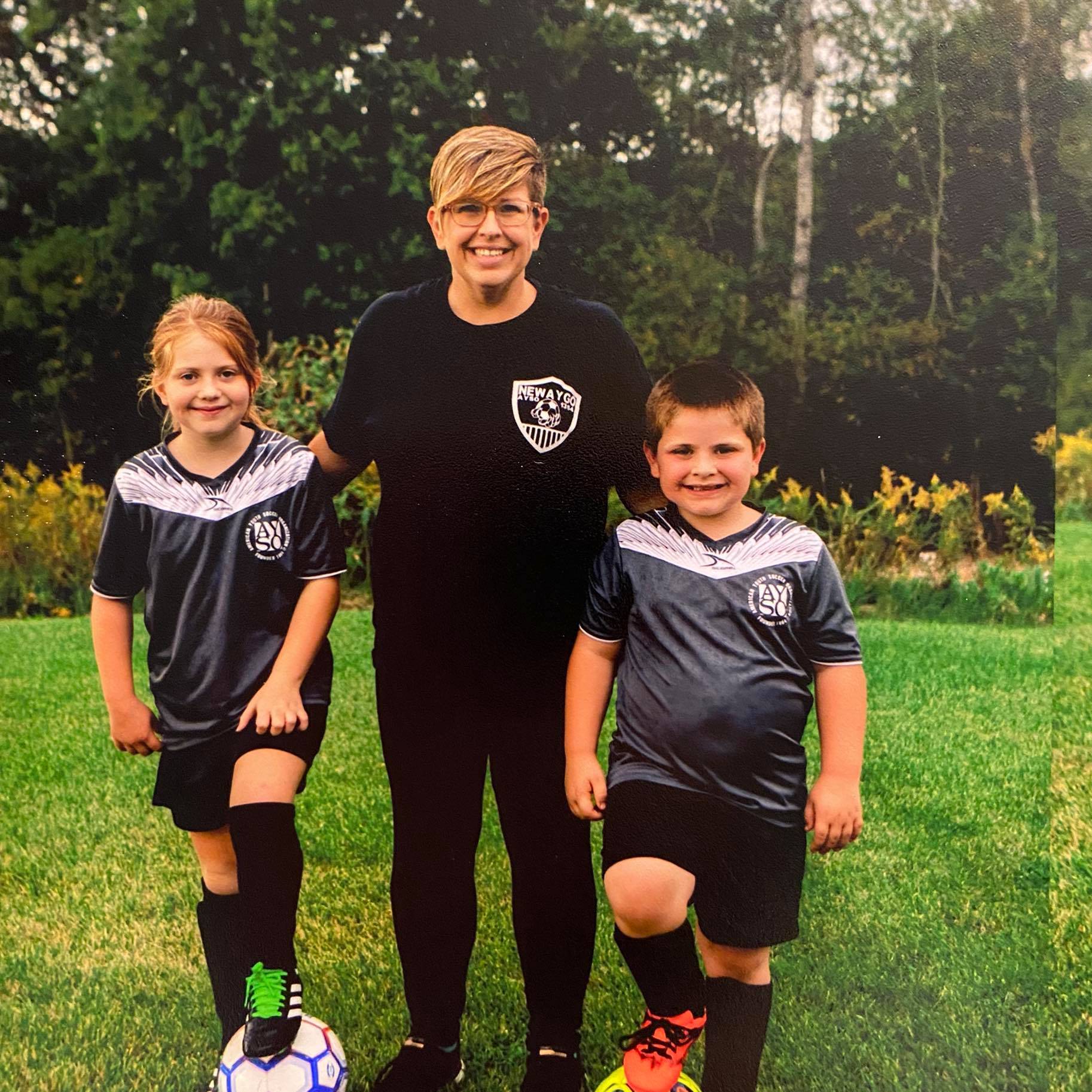 Erica Herwig standing with her two children in their soccer jerseys
